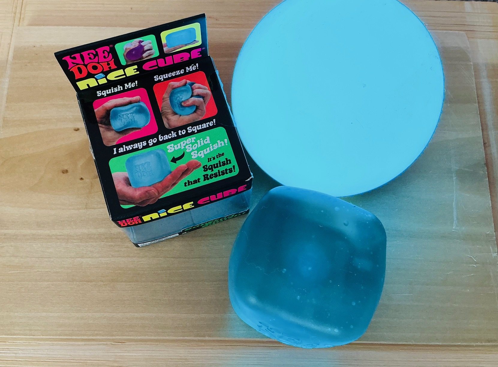 Blue NeeDoh Nice Cube returning to shape beside its package
